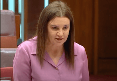 Jacqui wears a pink shirt asking a question in the Senate