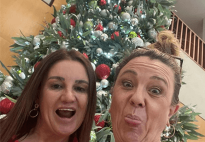 Jacqui and Tammy make a face in front of a Christmas tree