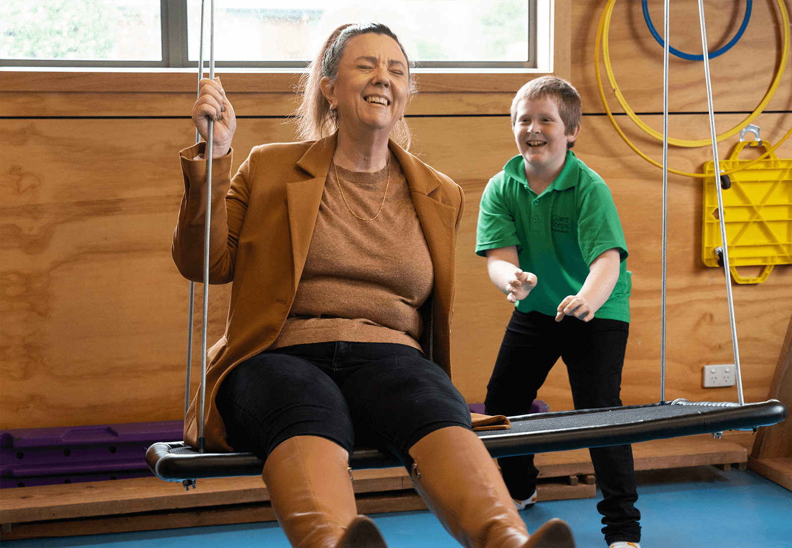 Tammy is being pushed on a swing by a young child at Giant Steps school in Deloraine