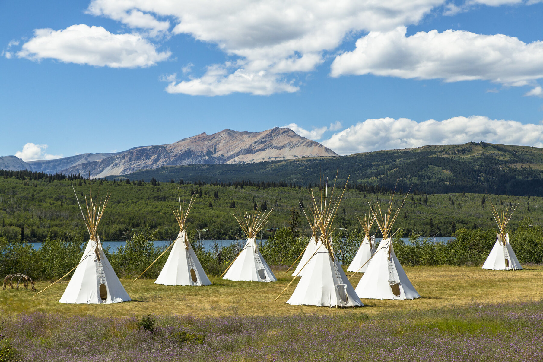 traditional indigenous lodges, also known as teepees with Glacier in the background