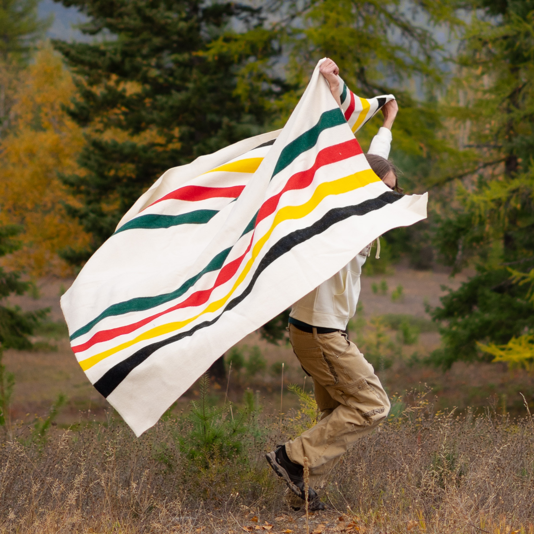 man running holding a pendleton glacier stripe blanket behind him