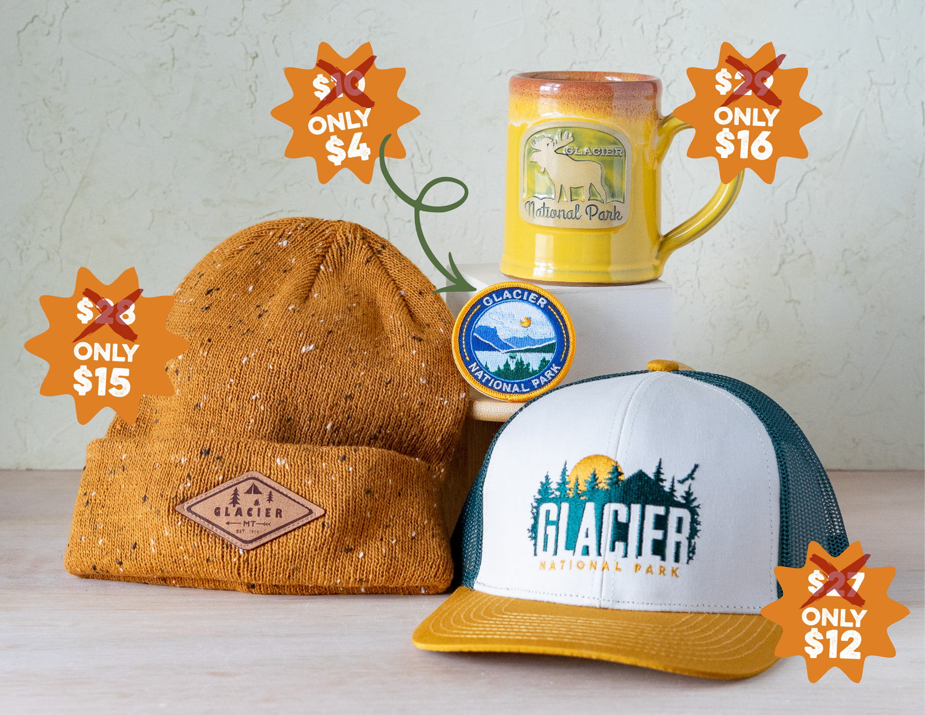 a grouping of products including a mustard beanie, a patch, a yellow pottery mug with a moose and a hat